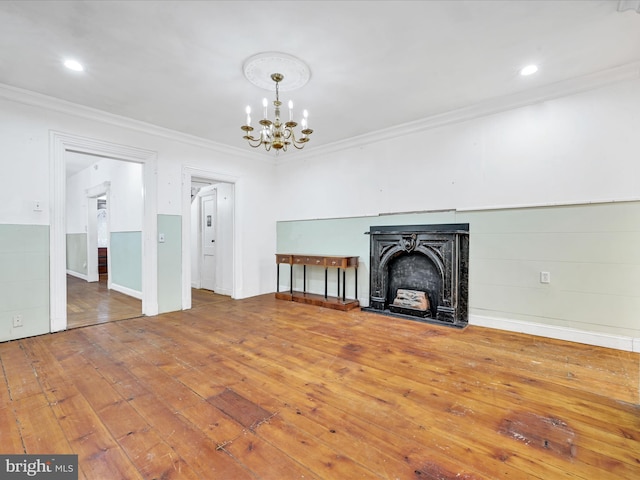 unfurnished living room featuring hardwood / wood-style floors, a notable chandelier, and ornamental molding