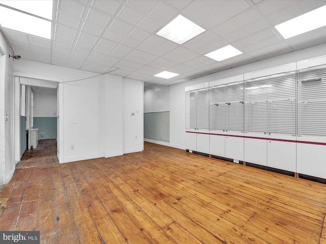 basement featuring a paneled ceiling and wood-type flooring