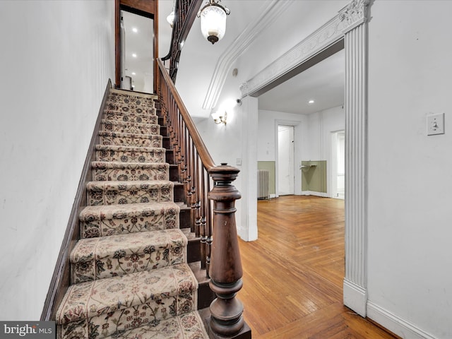 stairs featuring radiator, crown molding, and parquet floors