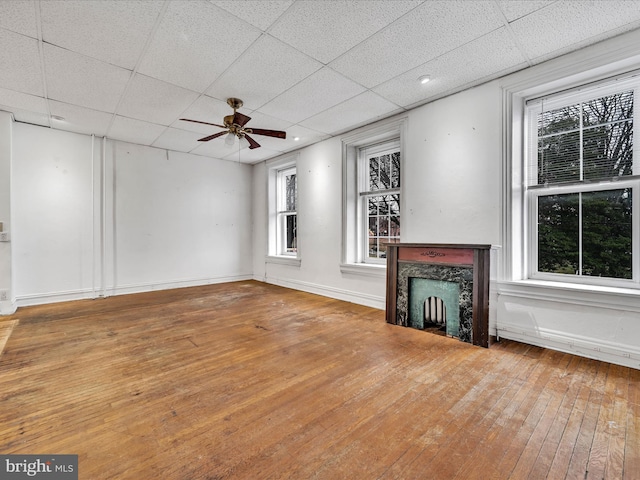 unfurnished living room with hardwood / wood-style flooring, a drop ceiling, ceiling fan, and a fireplace