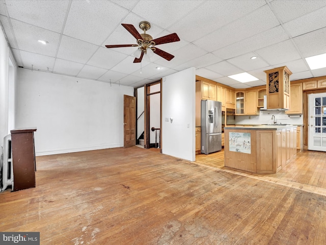 kitchen featuring stainless steel fridge, light wood-type flooring, light brown cabinetry, ceiling fan, and a kitchen island