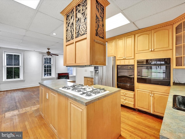 kitchen featuring stainless steel fridge, black oven, white gas stovetop, and light hardwood / wood-style floors