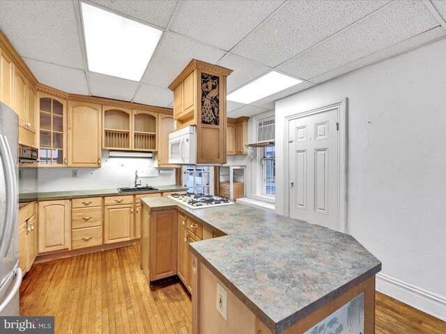 kitchen with a center island, white appliances, sink, and light hardwood / wood-style flooring