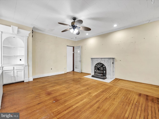 unfurnished living room with hardwood / wood-style flooring, ceiling fan, crown molding, and a high end fireplace