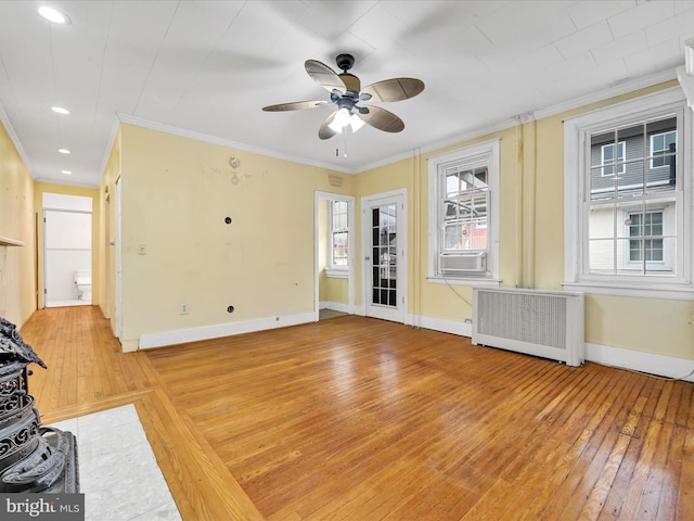 unfurnished living room featuring radiator heating unit, light wood-type flooring, ceiling fan, and ornamental molding