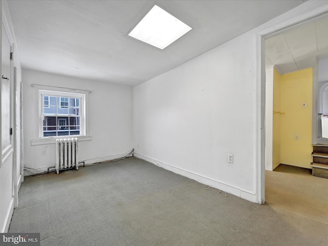 empty room featuring light carpet and radiator heating unit