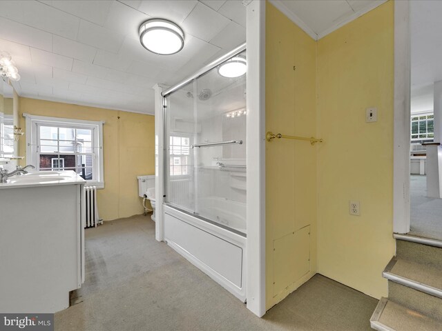 full bathroom featuring radiator heating unit, vanity, toilet, and enclosed tub / shower combo