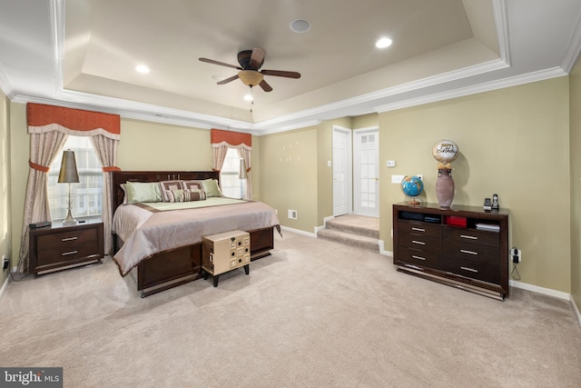 carpeted bedroom with a raised ceiling, multiple windows, ornamental molding, and ceiling fan