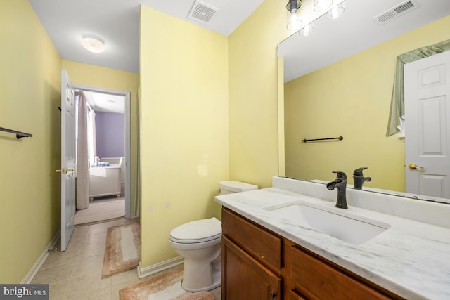 bathroom with toilet, vanity, and tile patterned floors