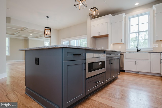 kitchen featuring white cabinetry, hanging light fixtures, plenty of natural light, a kitchen island, and light wood-type flooring