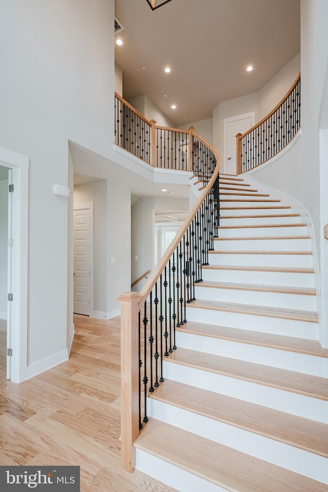 stairs with wood-type flooring and a high ceiling