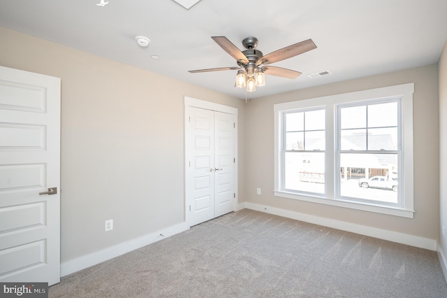 unfurnished bedroom with light colored carpet, a closet, and ceiling fan