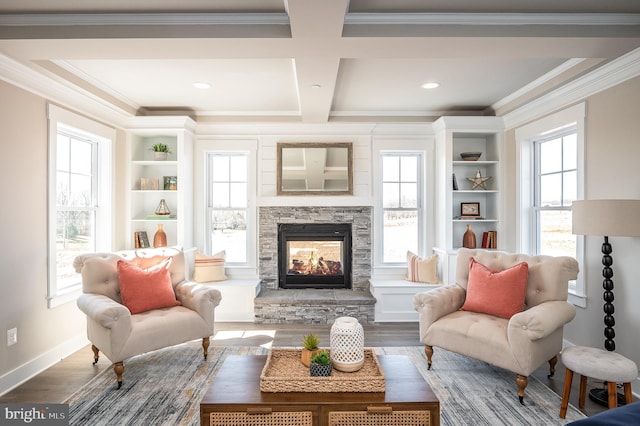 sitting room with dark wood-type flooring, beam ceiling, coffered ceiling, ornamental molding, and a stone fireplace