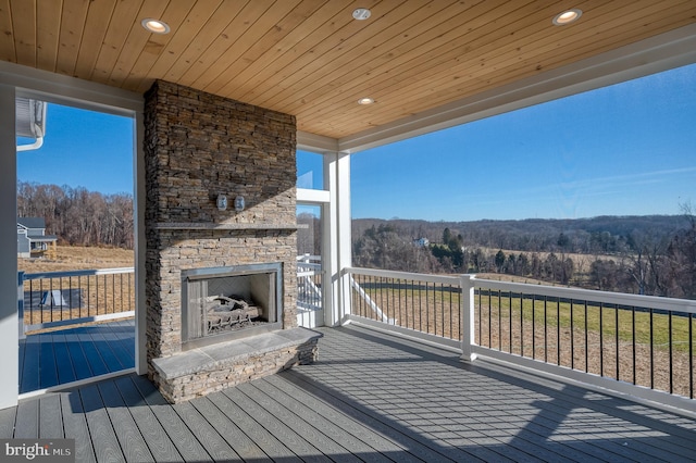 wooden deck featuring an outdoor stone fireplace