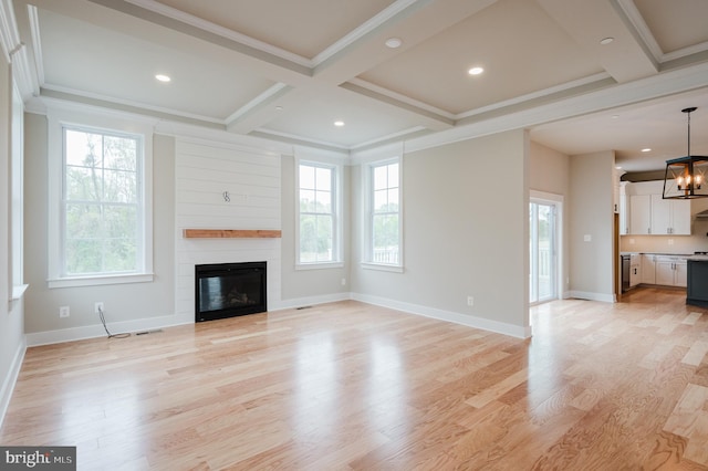 unfurnished living room featuring beamed ceiling, ornamental molding, coffered ceiling, and light hardwood / wood-style floors