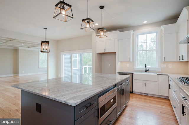 kitchen featuring hanging light fixtures, a center island, white cabinets, and appliances with stainless steel finishes