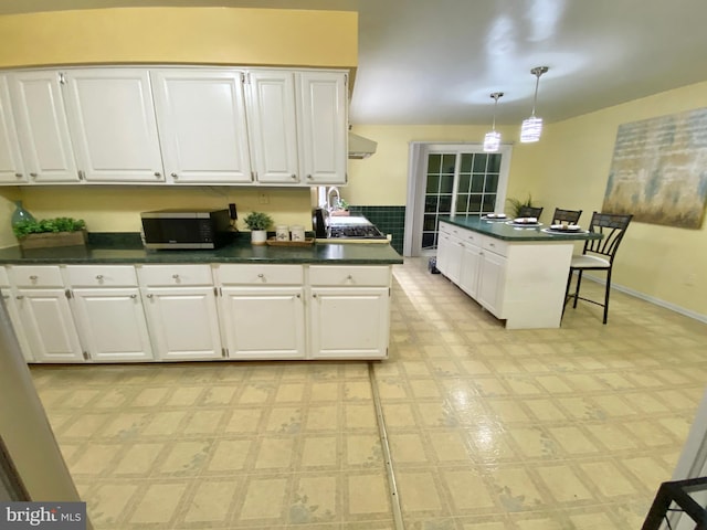 kitchen featuring white cabinets, pendant lighting, and extractor fan