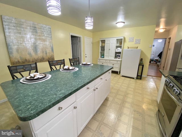 kitchen featuring hanging light fixtures, a kitchen island, a kitchen breakfast bar, white cabinets, and appliances with stainless steel finishes