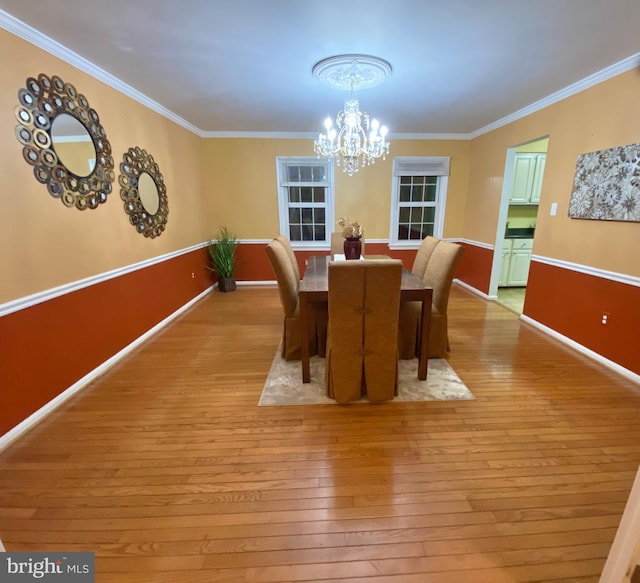 dining area with an inviting chandelier, crown molding, and light hardwood / wood-style flooring