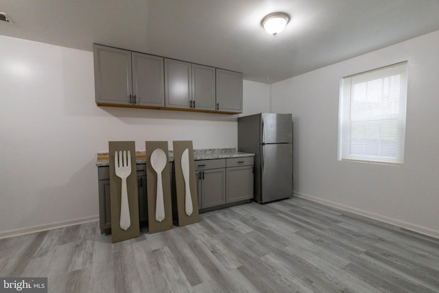 kitchen with gray cabinetry, stainless steel fridge, and light wood-type flooring