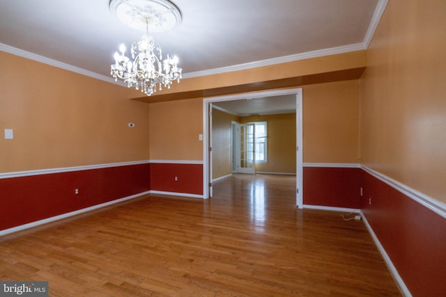 unfurnished room with hardwood / wood-style flooring, crown molding, and a chandelier