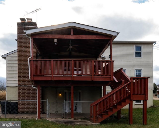 back of house featuring a lawn, ceiling fan, and a deck