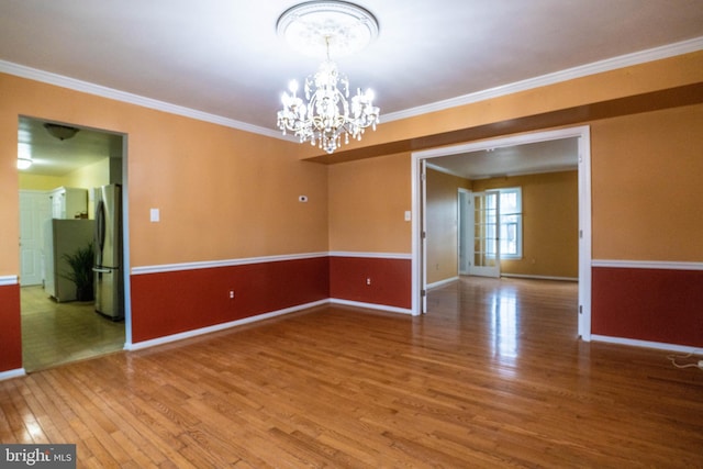 spare room featuring a chandelier, wood-type flooring, and crown molding