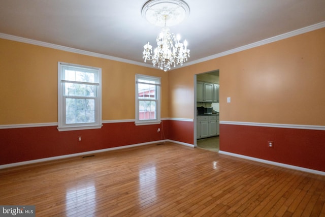 empty room with an inviting chandelier, ornamental molding, and light wood-type flooring