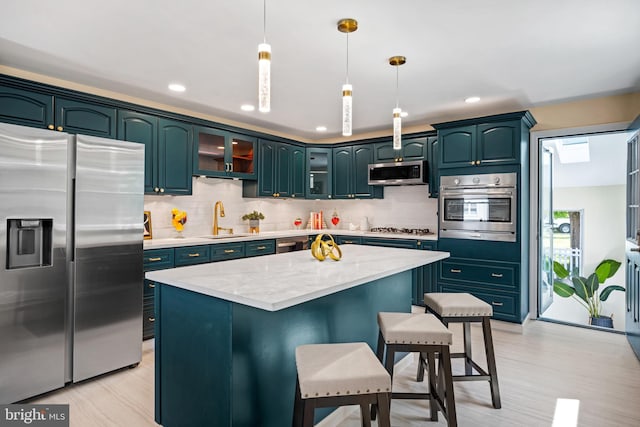 kitchen with pendant lighting, a center island, sink, appliances with stainless steel finishes, and tasteful backsplash