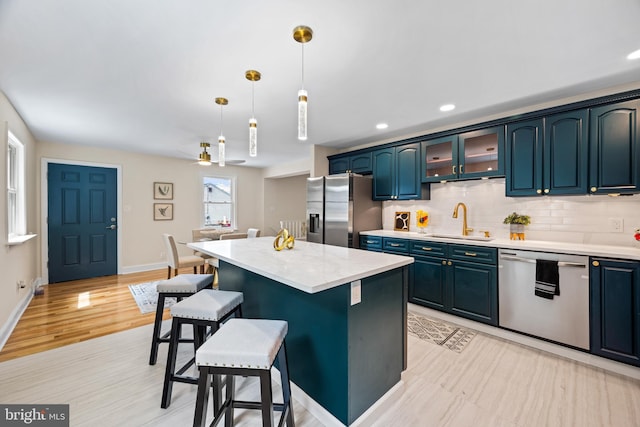 kitchen featuring stainless steel appliances, ceiling fan, sink, a center island, and hanging light fixtures