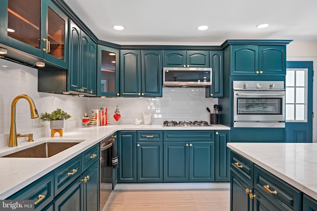 kitchen featuring sink, stainless steel appliances, light stone counters, backsplash, and light hardwood / wood-style floors