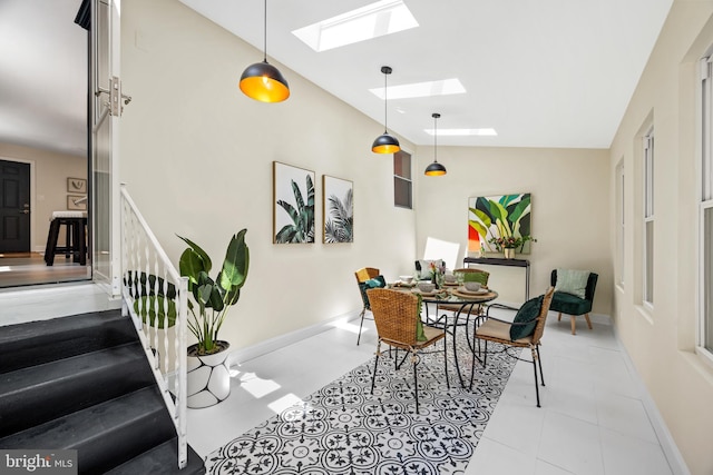 tiled dining space with lofted ceiling with skylight