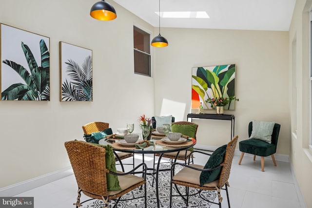 tiled dining space with lofted ceiling with skylight