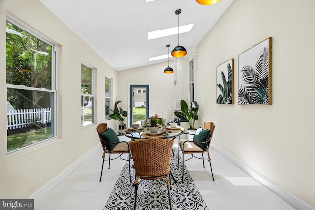 dining area with light tile patterned floors, lofted ceiling with skylight, and plenty of natural light