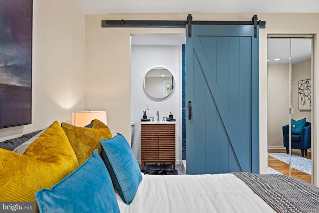 bedroom featuring hardwood / wood-style floors, a barn door, and sink