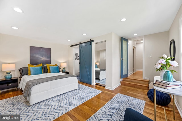 bedroom featuring hardwood / wood-style floors, a barn door, and connected bathroom