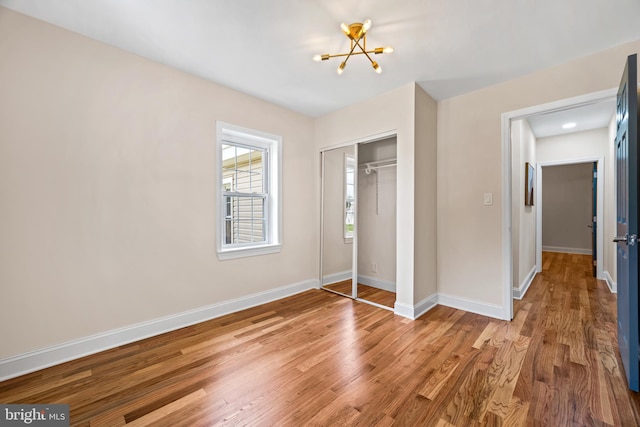 unfurnished bedroom with a chandelier, a closet, and wood-type flooring