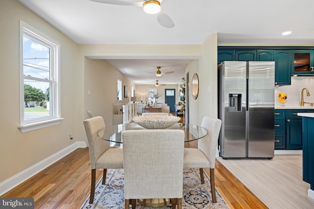 dining area with ceiling fan, sink, and light hardwood / wood-style flooring