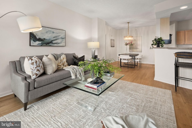 living room with an inviting chandelier and light wood-type flooring