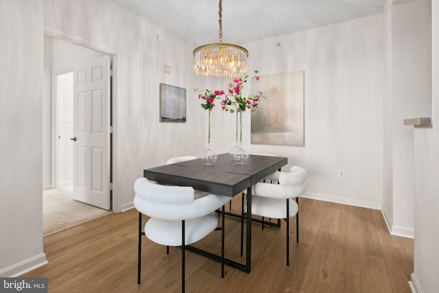 dining space with light hardwood / wood-style flooring and a notable chandelier