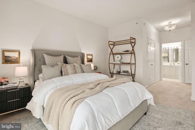 carpeted bedroom with ensuite bathroom and an inviting chandelier