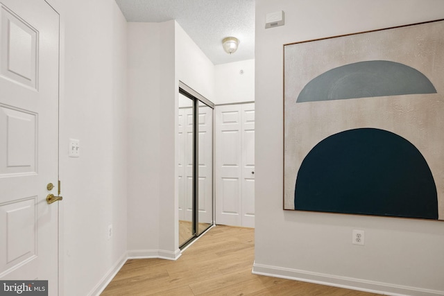 hall featuring a textured ceiling and light wood-type flooring