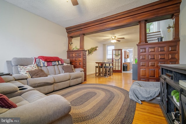 living room with ceiling fan, wood-type flooring, and a textured ceiling