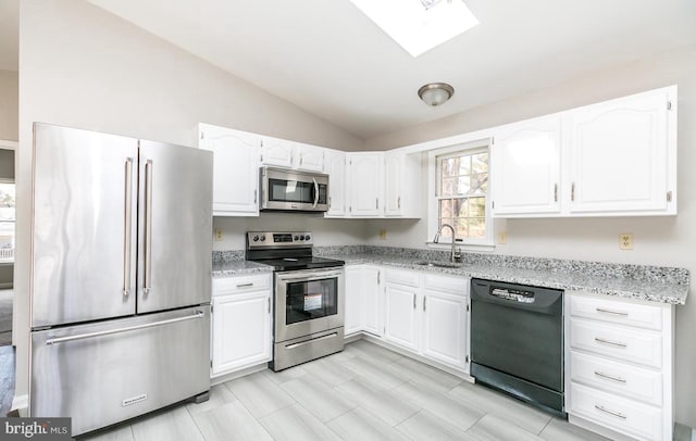 kitchen with white cabinets, stainless steel appliances, and lofted ceiling with skylight