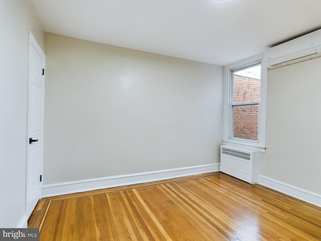 unfurnished bedroom with hardwood / wood-style floors and a wall unit AC