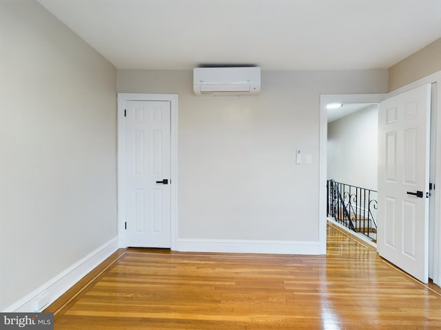 spare room featuring a wall mounted air conditioner and hardwood / wood-style flooring