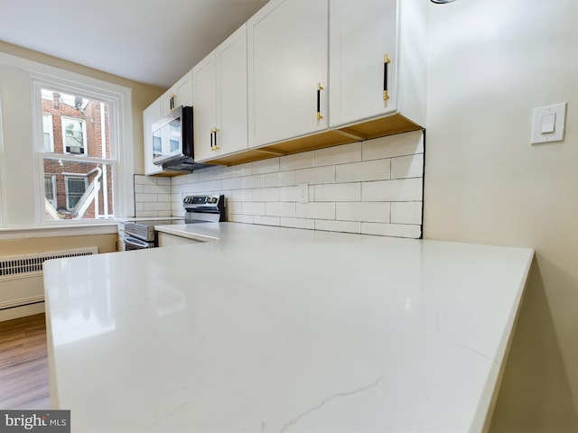 kitchen featuring white cabinetry, stainless steel electric range oven, radiator heating unit, light stone countertops, and light wood-type flooring