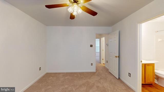 unfurnished bedroom featuring light carpet, ensuite bathroom, and ceiling fan