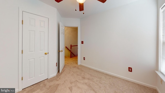 unfurnished bedroom with light colored carpet and ceiling fan