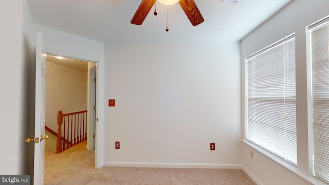 empty room featuring ceiling fan and light carpet